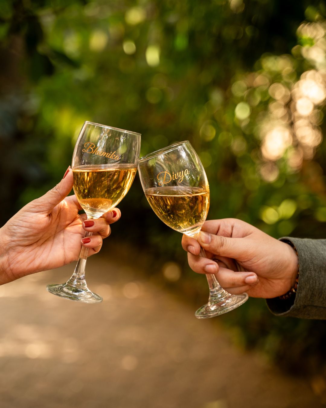 Two stemmed wine glasses with gold name engravings 'Bhunika' and 'Diya'