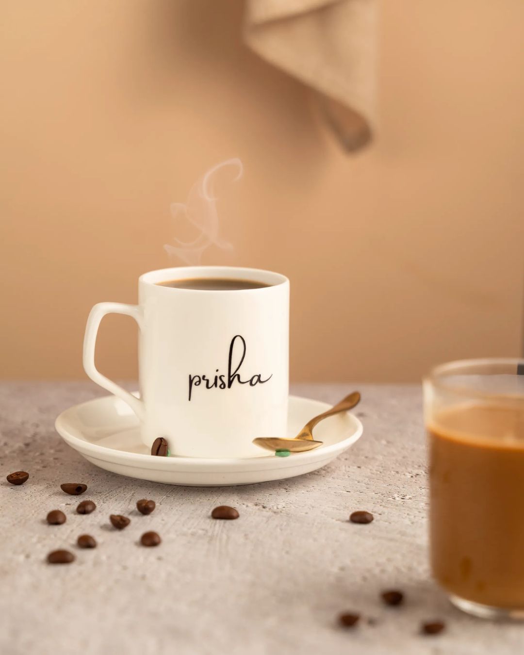 Ceramic mug and saucer with 'prisha' monogram in black, steam rising