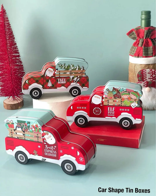 Car-shaped Santa-themed tin boxes with red, green, and plaid vehicle lids on display