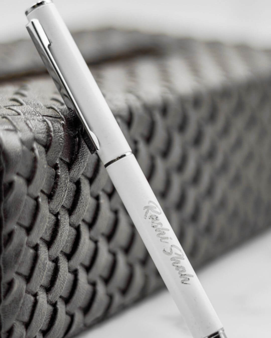 Light-colored personalized pen with silver clip and engraved lettering