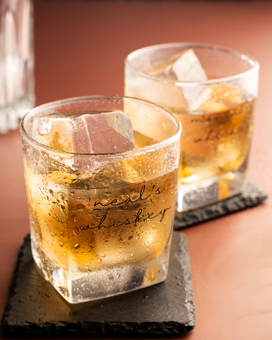 Lineage Pour whiskey glass with ice, amber drink, and etched “whiskey” lettering