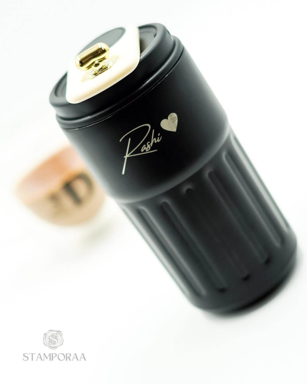 Black sipper tilted view with gold flip lid and 'Kashi' heart logo