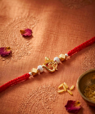 Red thread OM Rakhi bracelet with gold-toned OM charm and white bead accents