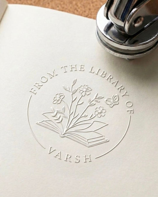 Floral library embossing seal impression on paper with book icon and 'FROM THE LIBRARY OF'