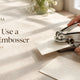 Hands sliding card into a paper embosser, how to use a paper embosser