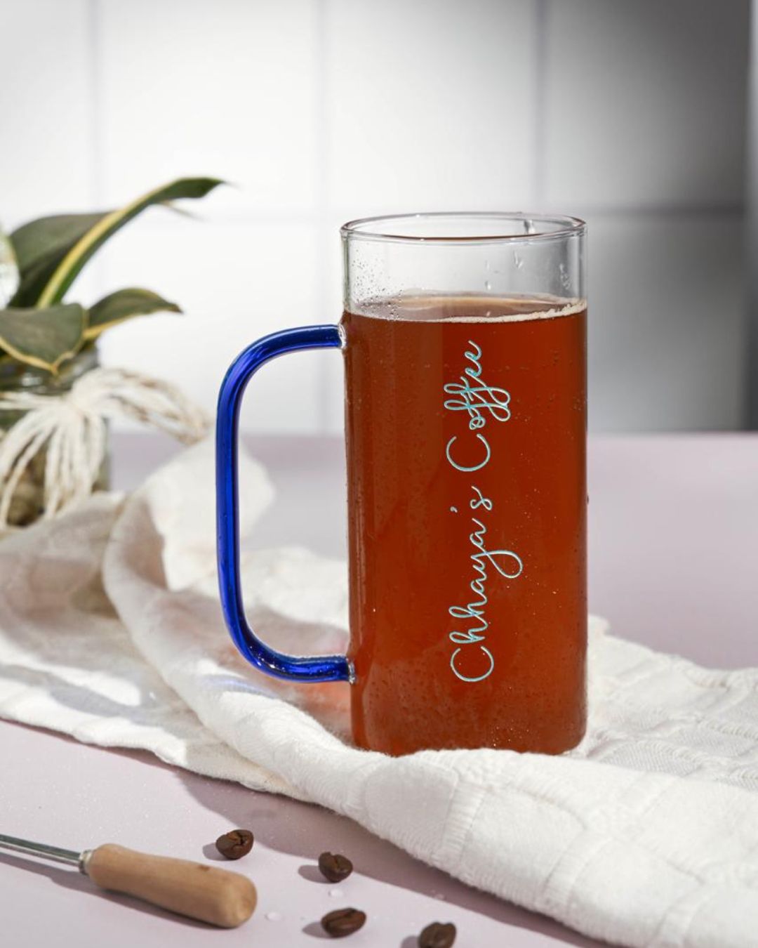 Tall glass with cobalt-blue handle, custom engraved script, amber drink
