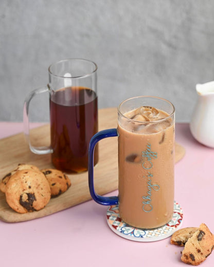 Tall glass with blue handle, custom engraved script, iced coffee with foam