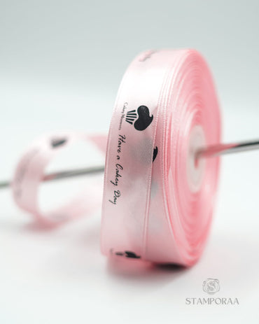Rosa Satinband mit schwarzem Logo und Text, auf Spule gewickelt