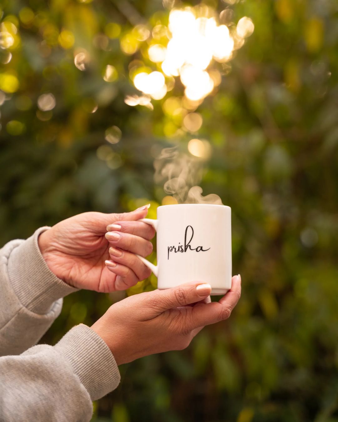 Ceramic mug held in hands, 'prisha' monogram in black