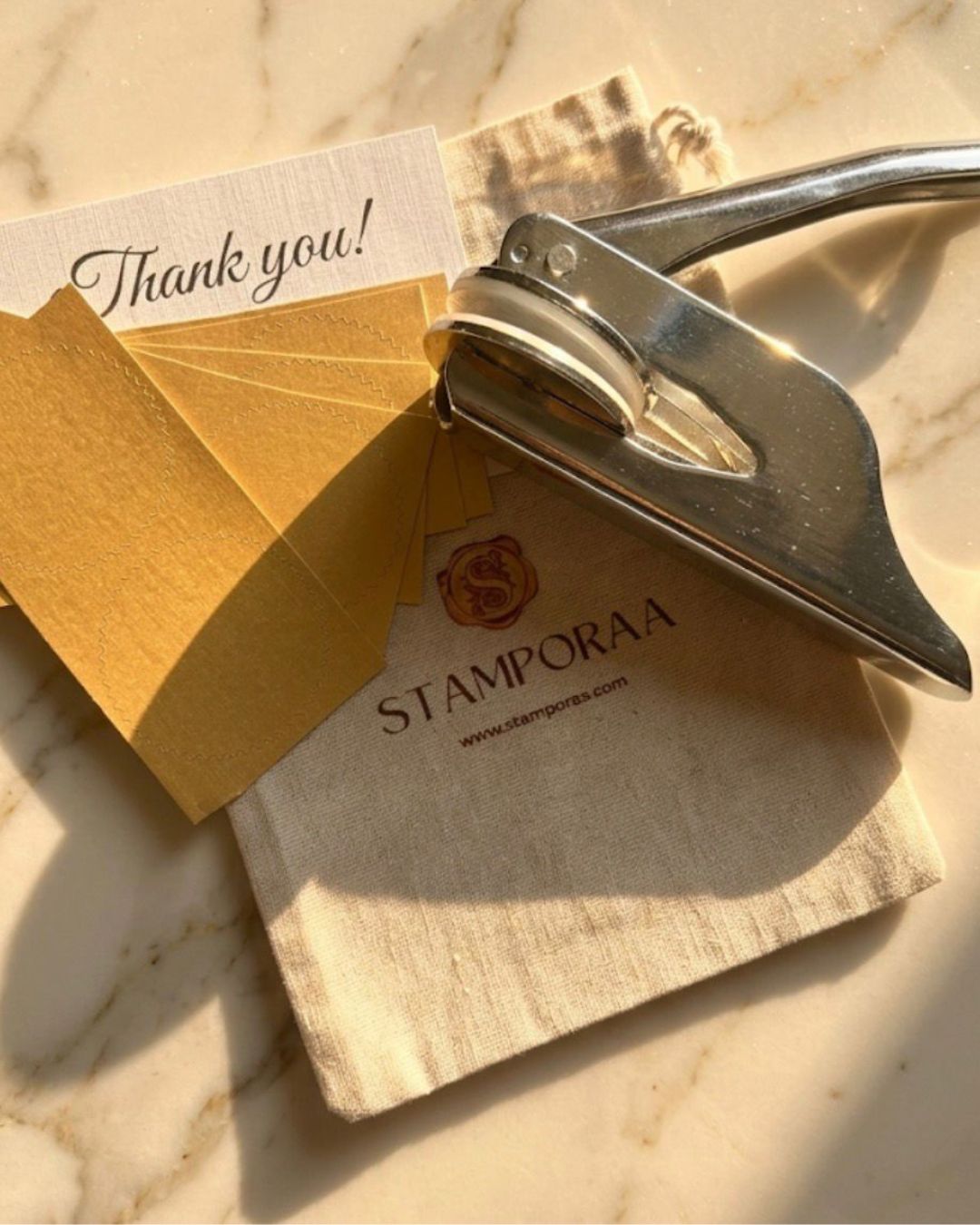 Paper embossing tool pressing a seal onto a thank-you note and envelope