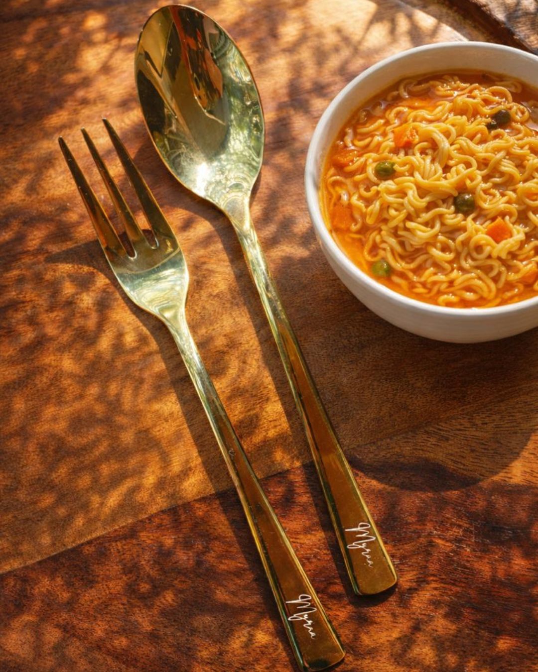 Personalized gold flatware set: engraved fork and spoon beside bowl