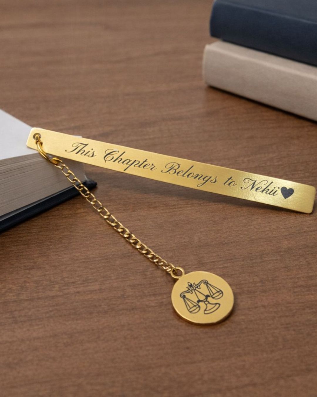 Gold metal bookmark reading “This Chapter Belongs to Nehi” with zodiac scales pendant
