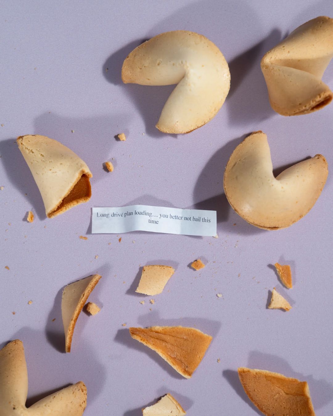 Assorted fortune cookies with a printed fortune slip and scattered crumbs