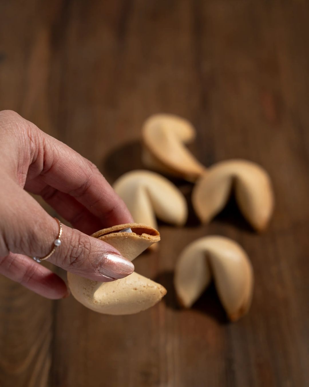 Hand placing a fortune cookie with a printed folded fortune slip