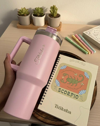 Pink tumbler and Scorpio journal on wooden board