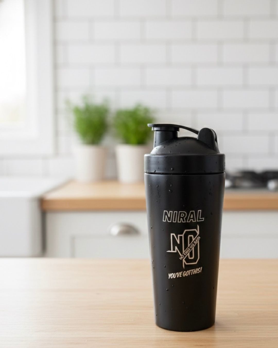 Matte black shaker bottle with flip-top spout and 'NIRAL' front logo