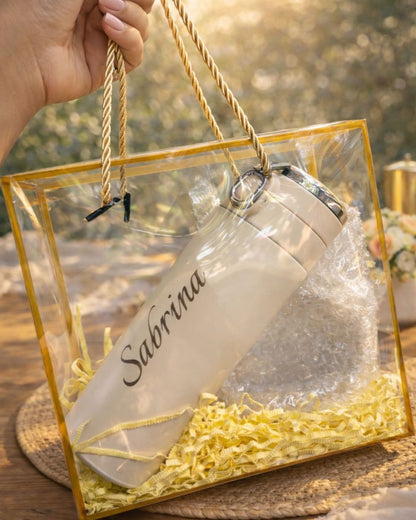 Beige bottle with gold 'Sabrina' engraving in gift box, held by ribbon