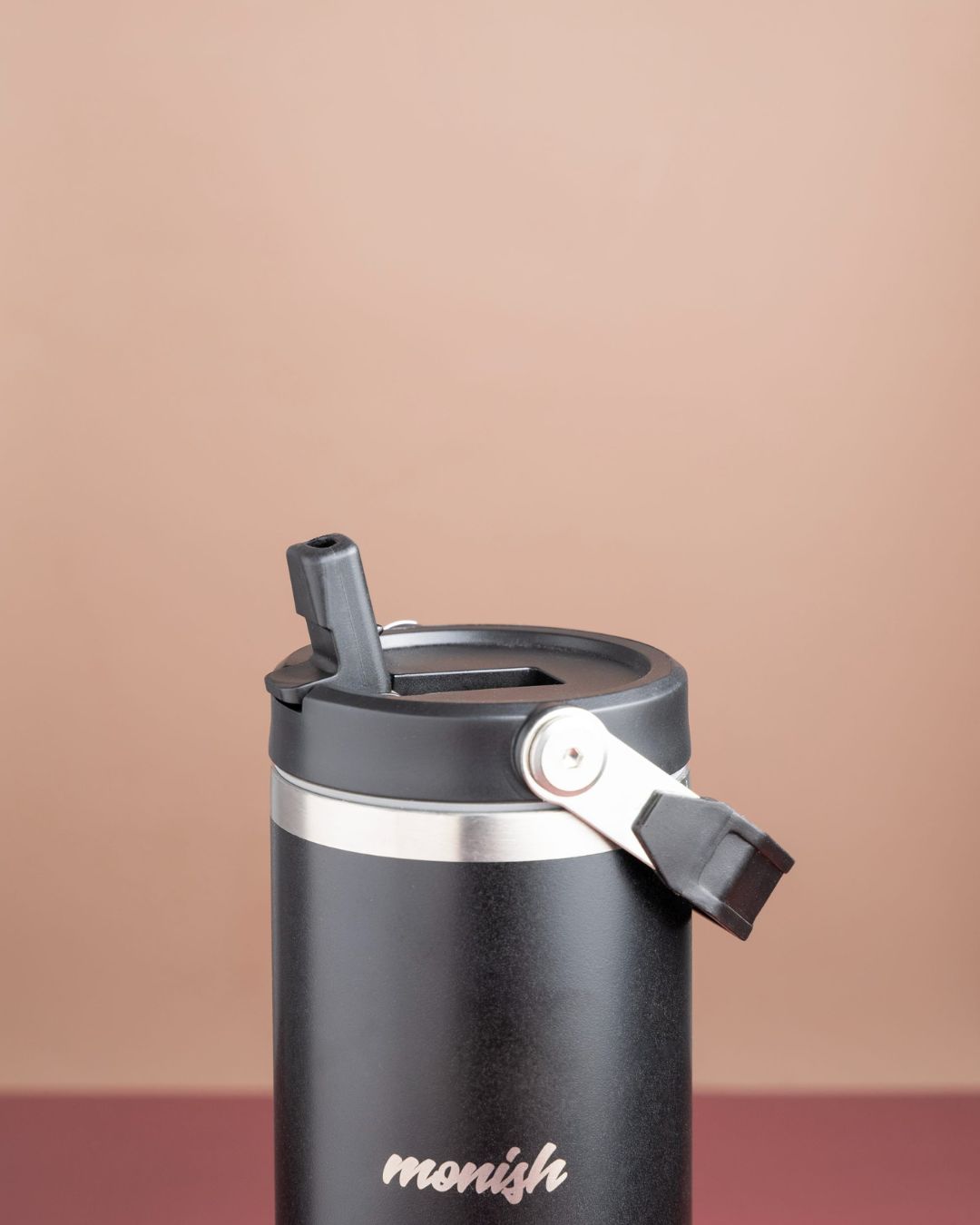 Black steel tumbler with flip-top lid and locking strap, front logo