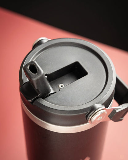 Black tumbler lid interior with drinking spout and latch mechanism, close-up