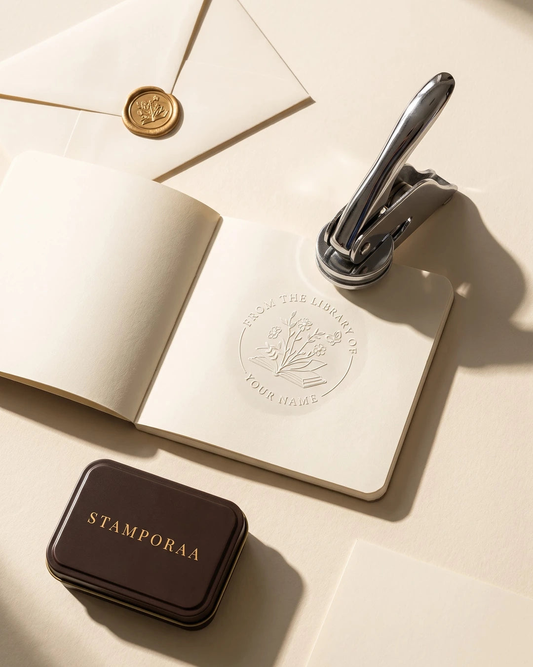 Floral paper embosser with metal handle over embossed round seal on stationery