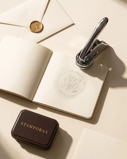 Floral paper embosser with metal handle over embossed round seal on stationery
