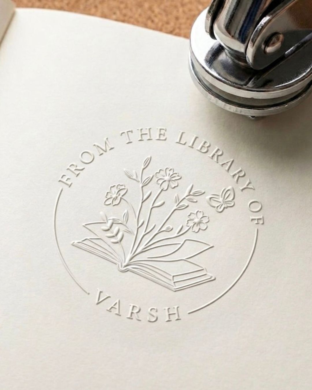 Floral library embossing seal impression on paper with book icon and 'FROM THE LIBRARY OF'