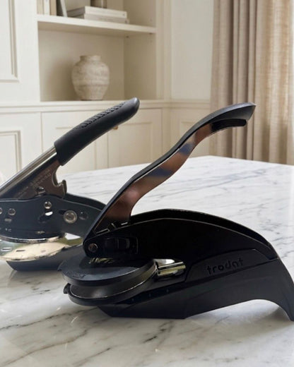 Tabletop paper embosser on marble surface, ready to press on paper