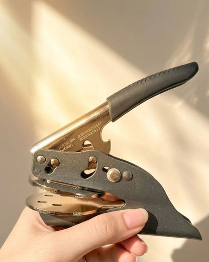 Handheld paper embosser with lever and base preparing to stamp cardstock